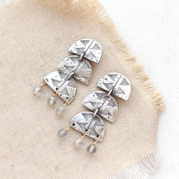 The pakal trio labradorite post earrings styled on tan linen
