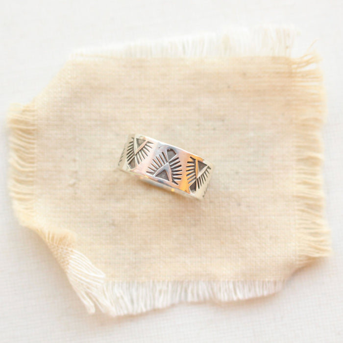 The stamped feathered wide band ring styled on tan linen