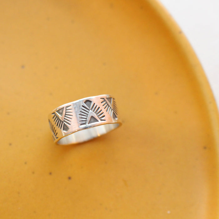 The stamped feathered wide band ring styled on a yellow plate