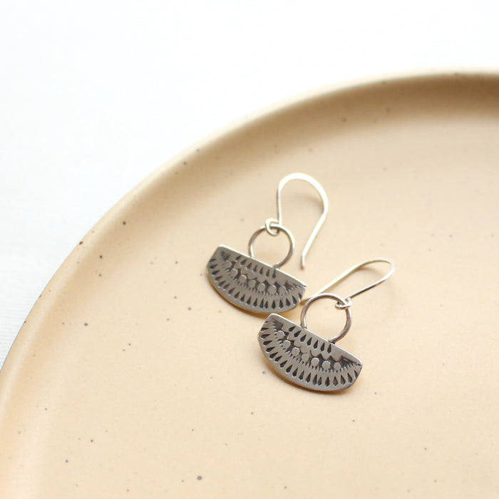 Stamped silver Asmi short loop earrings styled on a tan plate