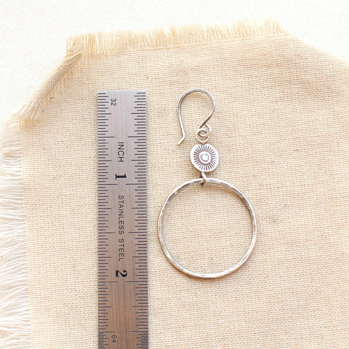 A talara sun hoop earring next to a ruler for size reference