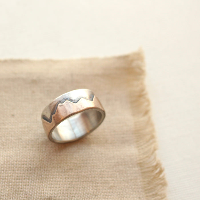 Oxidized bronze and silver mountain ring styled on tan linen