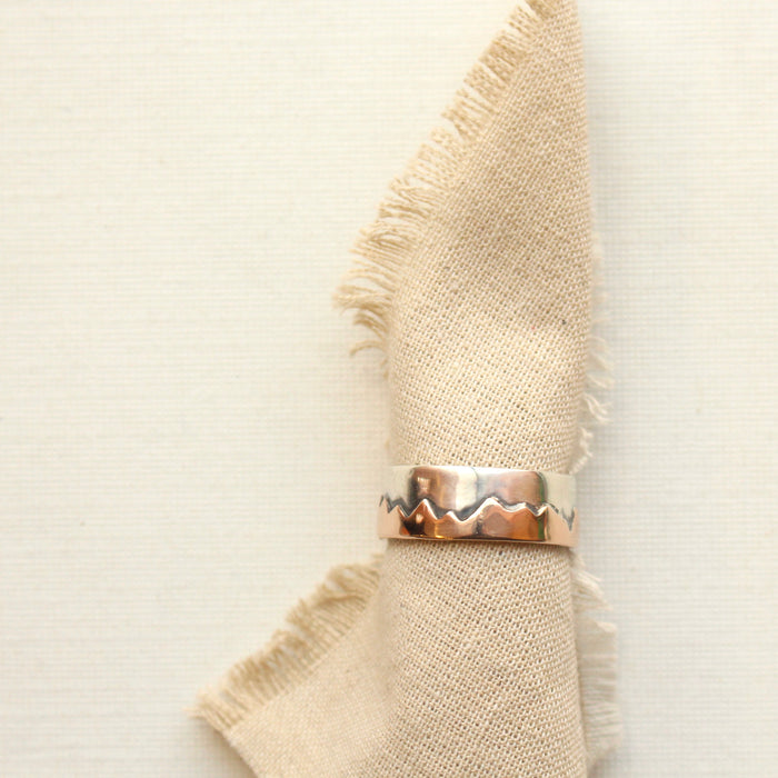 Polished bronze and silver mountain ring styled on rolled tan linen