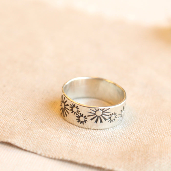 The sun stamped wide band ring styled on tan linen