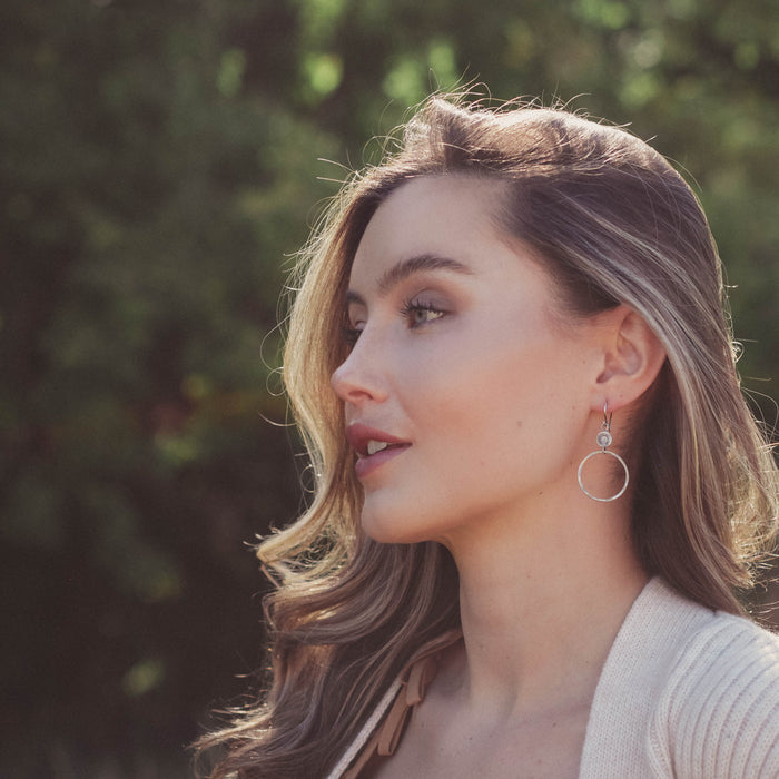 A model wearing the silver talara sun hoop earrings