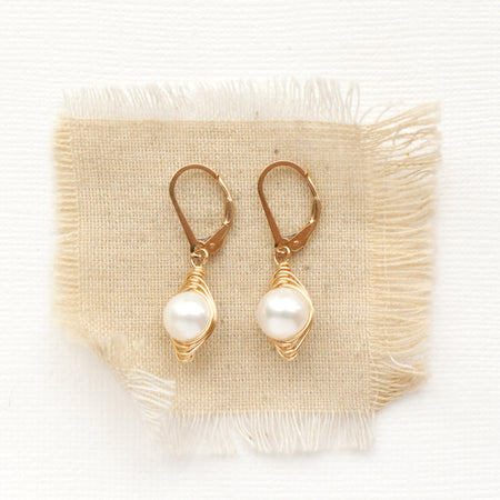 The perfect pearl gold wrapped earrings styled on tan linen