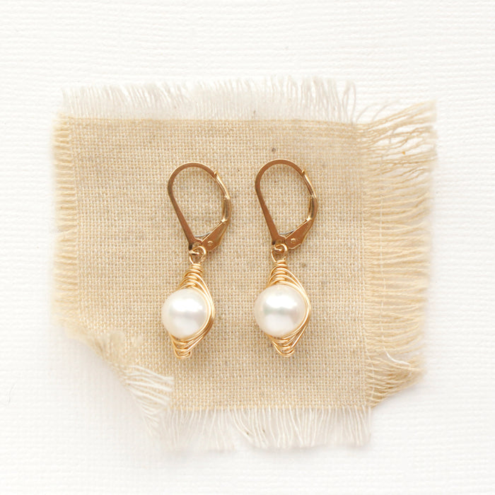 The perfect pearl gold wrapped earrings styled on tan linen