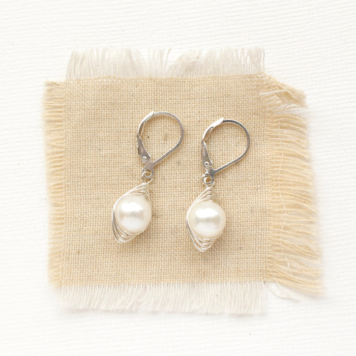 The perfect pearl silver wrapped earrings styled on tan linen