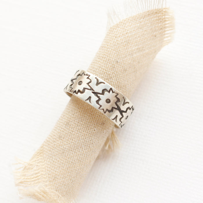 The arabesque stamped band ring styled on rolled tan linen