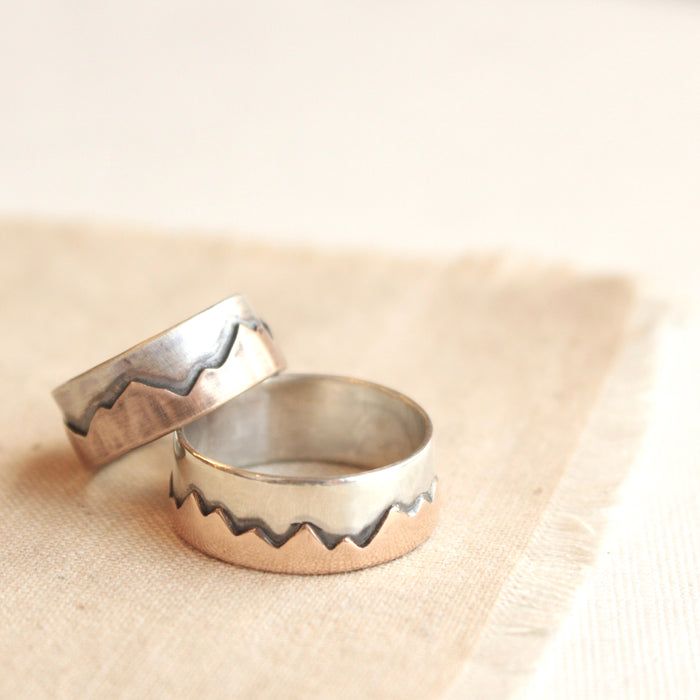 Bronze and silver mountian rings in both polished and oxidized styled on tan linen