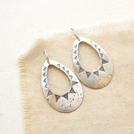 The southwest inspired pakal teardrop cutout earrings styled on tan linen