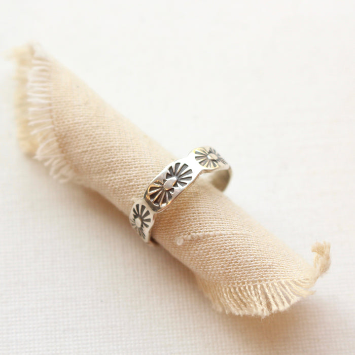 The stamped scalloped silver ring styled on a roll of tan linen