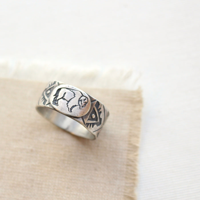 Stamped silver buffalo ring styled on tan linen