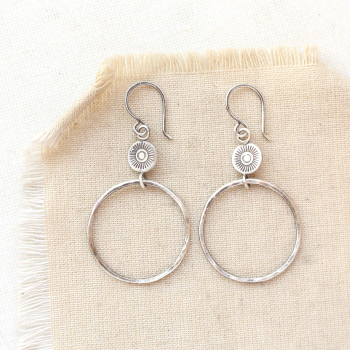 The silver talara sun hoop earrings styled on tan linen