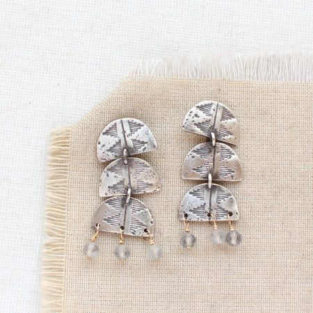 The pakal trio labradorite dangle post earrings styled on tan linen