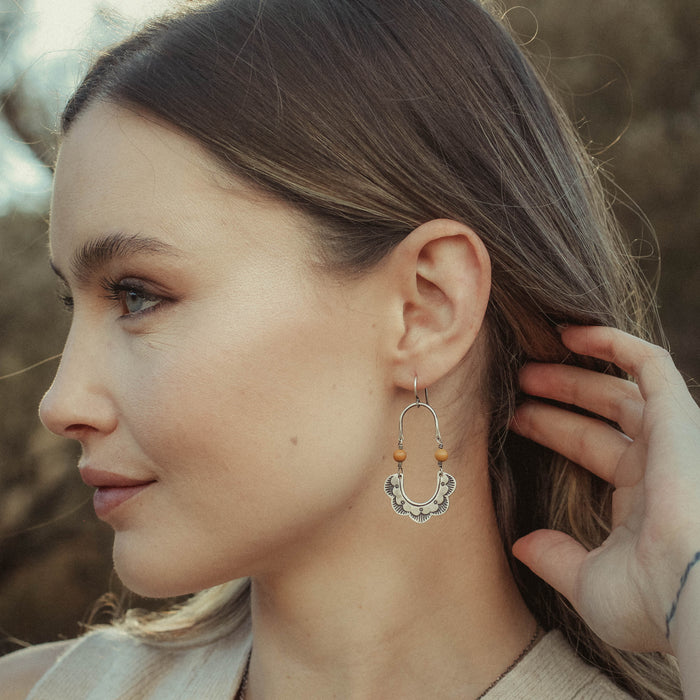 Model wearing the stamped silver columbine mookaite earrings
