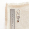 A brown zircon wanderer hoop earring next to a ruler for size reference