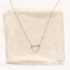 The floating silver heart necklace styled on tan linen