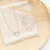 The silver floating heart necklace styled on a tan plate with the matching earrings 