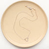 The floating silver heart necklace styled on a tan plate to show the adjustable lobster clasp closure