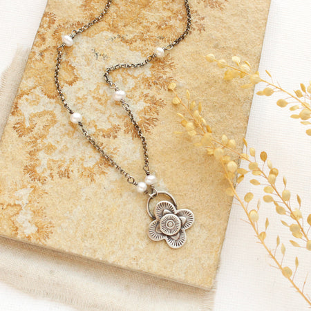 The Layered Talara Pearl Necklace styled on a tan rock with linen and dried grass