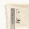 A pinned dune arch earring next to a ruler for size reference