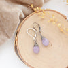 The kunzite drop earrings styled on wood with tan velvet and dried grass