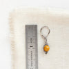 A perfect wrap yellow mookaite earring next to a ruler for size reference