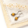 The perfect wrap yellow mookaite earrings styled on limestone with tan linen and dried grass