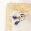 The perfect wrap lapis earrings styled on limestone with linen and dried grass