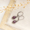 The perfect wrap purple ruby earrings styled on limestone with linen and dried grass