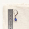 A perfect wrap lapis earring next to a ruler for size reference