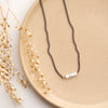 The sydney white howlite necklace styled on a tan plate with dried grass