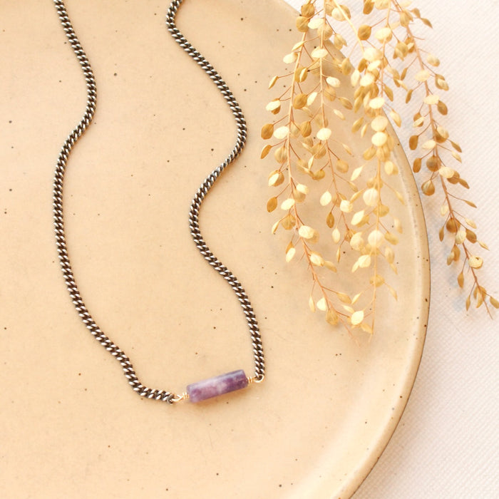 The sydney lepidolite necklace styled on a tan plate with dried grass