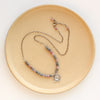 The layered cactus flower sapphire necklace styled on a tan plate to show the adjustable lobster clasp closure