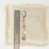 A mini cactus flower long desert earring next to a ruler for size reference