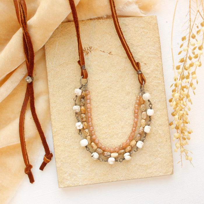 The layered desert adjustable leather necklace styled on a tan rock with gold velvet and dried grass