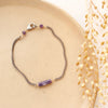 The sydney lepidolite bracelet styled on a tan plate with dried grass