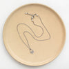 The mini talara shield necklace styled on a tan plate to show the adjustable lobster clasp closure