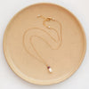The pearl and ruby gold necklace styled on a tan plate to show the adjustable lobster clasp closure