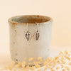 the little leaf lobe hugger earrings styled on a ceramic cup with dried grass