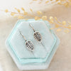 The little leaf lobe hugger earrings styled on a blue velvet box with linen and dried grass