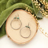 The african jasper halo hoop earrings styled on wood with green velvet and dried grass