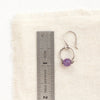 An amethyst la cloche earring next to a ruler for size reference