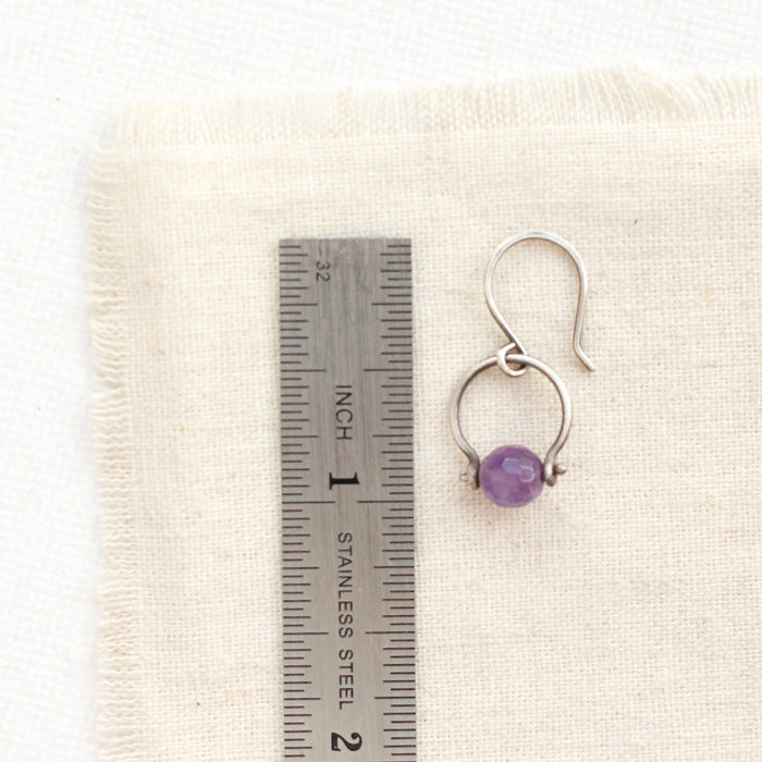 An amethyst la cloche earring next to a ruler for size reference