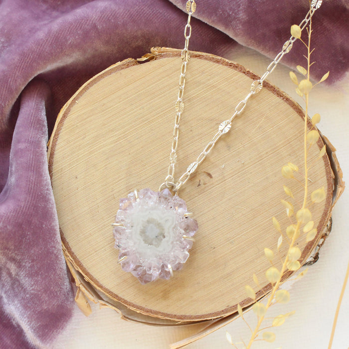 The amethyst stalactite flower necklace styled on wood with purple velvet and dried grass