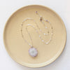 The amethyst stalactite flower necklace styled on a tan plate to show the adjustable lobster clasp closure