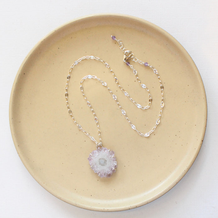 The amethyst stalactite flower necklace styled on a tan plate to show the adjustable lobster clasp closure