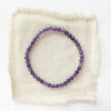 The amethyst stretch bracelet styled on tan linen