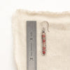 A andesine beaded bar earring next to a ruler for size reference